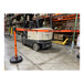 An orange Banner Stakes retractable barrier with "Danger-Forklift Traffic" text in a warehouse with a forklift.