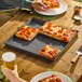 A square hard coat aluminum pizza pan holding several slices of Sicilian-style pepperoni pizza.