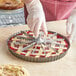 A person using a Choice aluminum pie and cake marker to cut a pie.