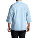 A man wearing a sky blue Uncommon Chef 3/4 length sleeve chef coat.