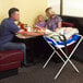 A man and woman eating at a table with a Koala Kare infant seat holding a baby.