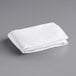 A folded white Oxford Super queen size fitted sheet on a gray surface.