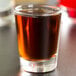 A Libbey shot glass filled with brown liquid.