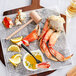 A Dungeness crab claw on a cutting board with a lemon slice.