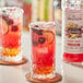 Two glasses of red drinks with cherries and a Monin HomeCrafted Cherry Smash label.