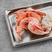 A cluster of frozen Dungeness crab legs on a stainless steel tray.