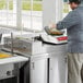 A man in a chef's uniform stir-frying food in a wok on a countertop induction range.