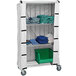 A Quantum white nylon cart cover on a white cart over shelves with white and blue towels.