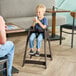 A brown assembled high chair designed for children, shown in use at a restaurant table.