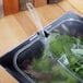 A Carlisle clear plastic food pan lid with a spoon notch on a plastic container on a counter.