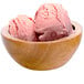 A wooden bowl with two scoops of G.S. Gelato strawberry gelato.