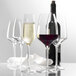 A group of Stolzle Bordeaux wine glasses on a table with a bottle of wine.