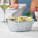 An American Metalcraft round galvanized metal tub filled with ice and lemon slices on a table with a bucket of oysters and lemons.