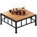 A Cal-Mil iron black square riser with a bamboo top on a wooden table with chocolate balls on it.