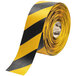 A roll of yellow and black tape with black chevrons and a warning sign.