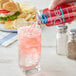 A hand pouring Ocean Spray Diet Sparkling Cranberry Juice into a glass of ice.