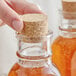 A person's hand corking a jar of honey.