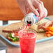 A hand pours Ocean Spray Sparkling Cranberry Juice from a can into a glass.