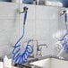A Waterloo pet grooming faucet with blue and silver hoses and a shower head on the wall.