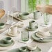 A table set with sage green Acopa Pangea plates and cups.