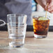 A person holding a straw in an Acopa Select stackable rocks glass filled with water.