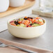 A close-up of a white Acopa Pangea nappie bowl filled with a salmon avocado salad.