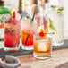 A variety of Acopa Rocks glasses filled with drinks and ice on a bar.