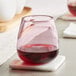 An Acopa mauve stemless wine glass filled with red wine sits on a coaster.