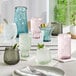 A table with Acopa Pangea mauve stemless wine glasses and different colored glasses and utensils.