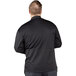 A man wearing a Uncommon Chef black long sleeve chef coat with mesh back.