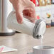 A hand pouring sugar from a Choice glass jar into a white cup.