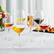 A group of Acopa Silhouette flute glasses on a table with a glass of red wine and a plate of fruit.