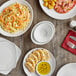 A table with Acopa bright white square porcelain coupe plates full of food.