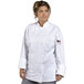 A woman wearing a white Uncommon Chef long sleeve chef coat with mesh back.