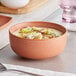 A sample Acopa Terra Cotta porcelain bowl filled with soup on a table.