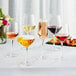 Acopa Silhouette wine glasses filled with red and white wine on a table with a plate of fruit.