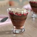 An 8 oz. stemless martini or dessert glass filled with a layered chocolate dessert, topped with whipped cream and pomegranate seeds.