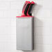 An Edlund stainless steel knife rack with red insert holding knives.
