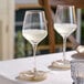 Two Acopa Silhouette wine glasses on a table with white wine.