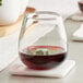 An Acopa Pangea stemless wine glass of red wine on a marble coaster.