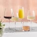 A table with Acopa Piatta stemless wine glasses and a glass of orange juice.