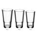 A row of empty Acopa Select stackable highball glasses.