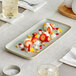 A rectangular white porcelain platter with strawberries and cream on it.