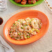 A plate of shrimp fried rice with broccoli on an Acopa Valencia orange stoneware coupe platter.