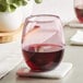 An Acopa mauve stemless wine glass filled with red wine sits on a coaster.