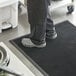 A person standing on a Lavex black rubber anti-fatigue mat.