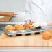 A person holding a Chicago Metallic jumbo crown muffin pan filled with muffins.