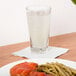 A Libbey Inverness beverage glass of water on a table with a plate of food.