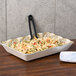 A mosaic melamine tray with a bowl of pasta and a fork on a table.