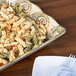 A Mosaic melamine tray with pasta salad and plastic forks on a table.